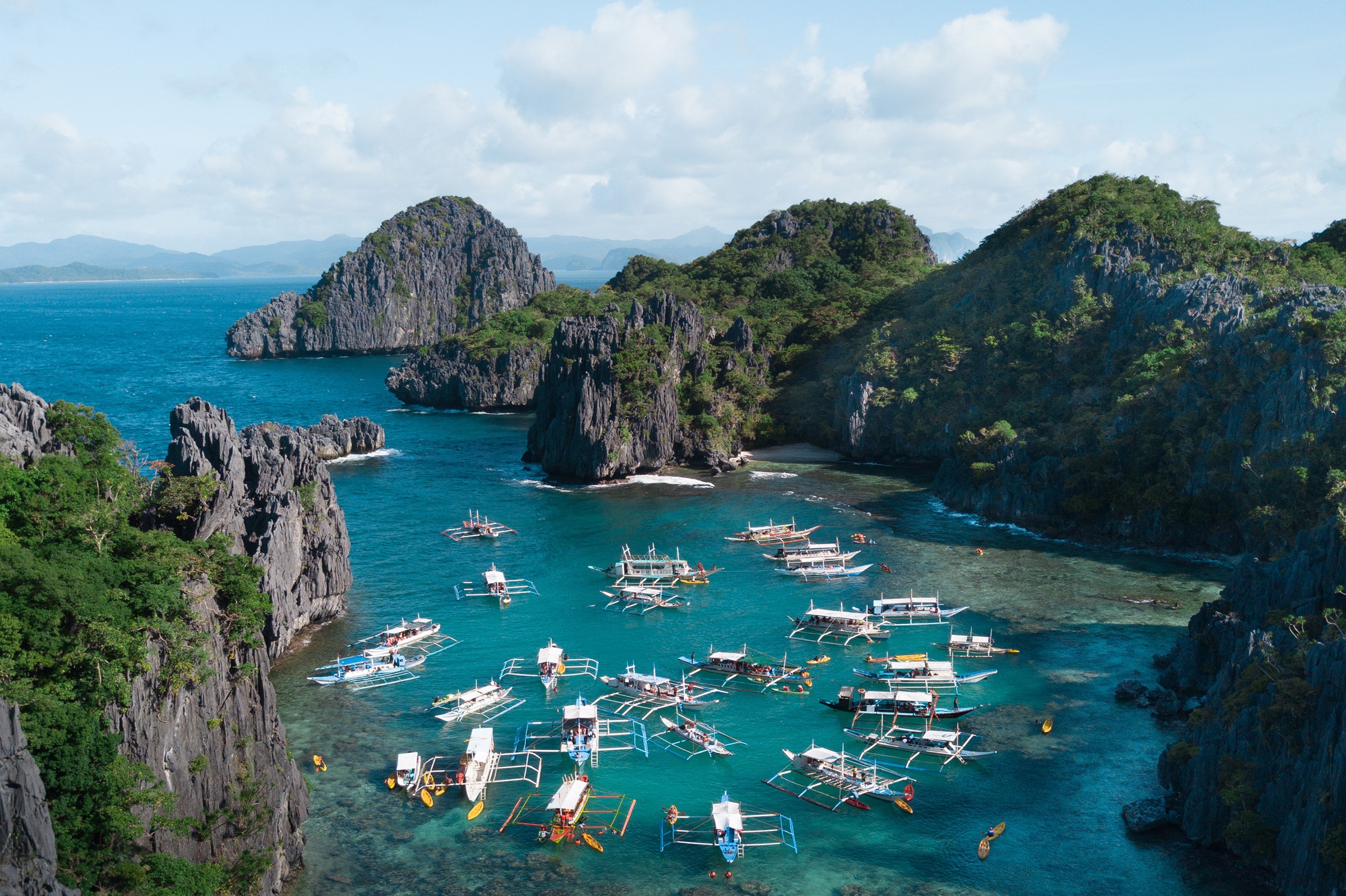 The boats on the ocean surrounded by mountains under the cloudy sky